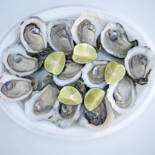 a plate of oysters with lime wedges