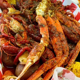 a plate of crab legs, corn, potatoes and corn on the cob