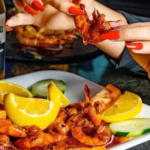 a plate of shrimp with lemon wedges