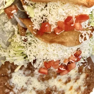 Hard-shell shredded beef tacos with delicious refried beans, classic and delicious.