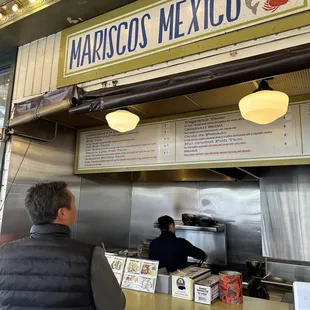 a man standing at the counter of a mexican restaurant