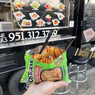 a hand holding a bag of chips