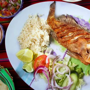 a plate of fish with rice and vegetables