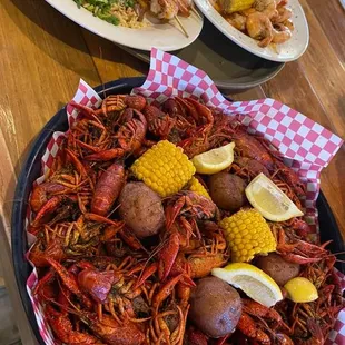 a plate of crawfish, corn, potatoes, corn on the cob, and corn on the cob