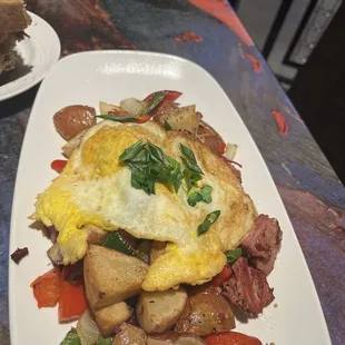 Corned beef hash with eggs, toast, peppers and onions