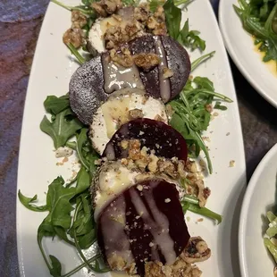 Beet salad with goat cheese on a bed of arugula with candied walnuts and a vinaigrette