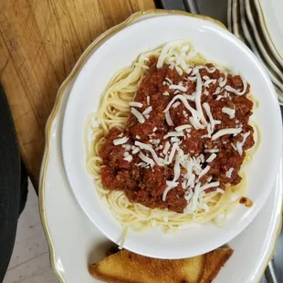 a plate of spaghetti with meat sauce and toasted bread