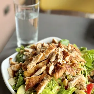 a plate of chicken salad and a glass of water