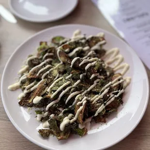 a plate of broccoli with a drizzle of white sauce