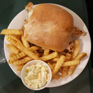 a chicken sandwich with fries and coleslaw