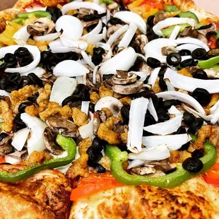 a pizza with mushrooms, onions, peppers, and olives