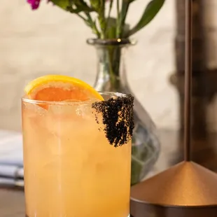 a glass of orange juice and a vase of flowers