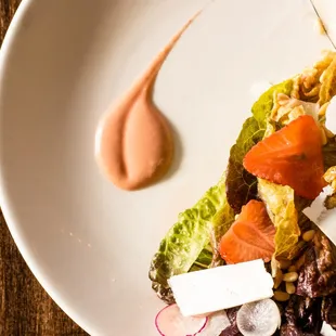 a plate of food with salmon, lettuce, tomatoes, and parmesan cheese