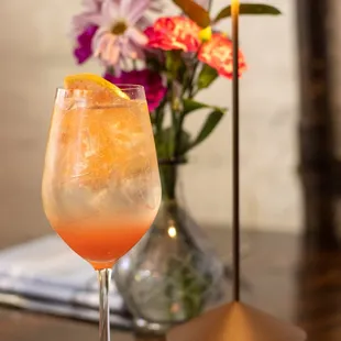 a glass of orange juice and a vase of flowers