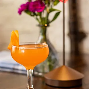 a glass of orange juice and a vase of flowers