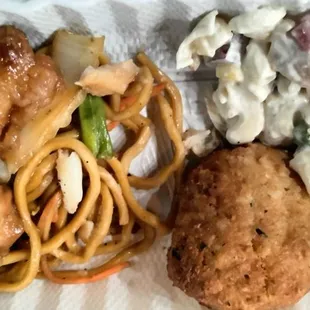 Orange chicken, lo mein, crab cake and macaroni salad with chicken in it.