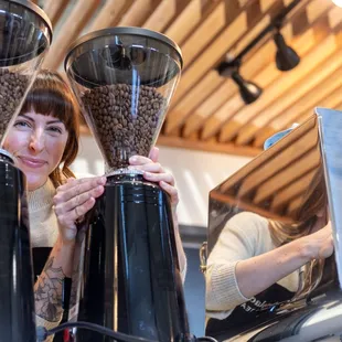a woman holding two coffee grinders