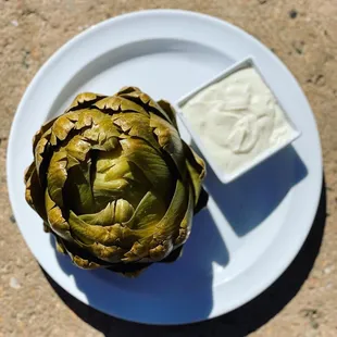 an artichoke on a plate with a dip