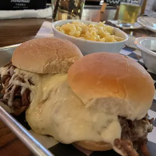 a plate of pulled pork sandwiches with macaroni and cheese