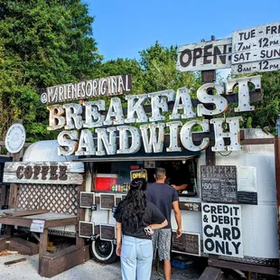 two people standing in front of a food truck