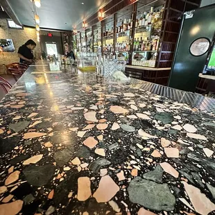 the floor of a restaurant with a bar in the background