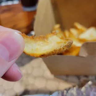 a hand holding a piece of french fries