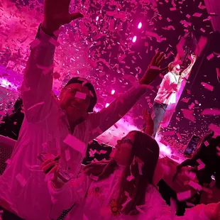 a man and woman in a party with confetti falling from the ceiling