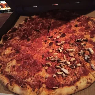 Humungous pepperoni pizza with mushrooms on a quarter of it.