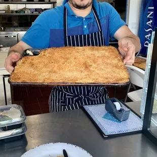 Owner Nars Muhammad (perhaps owner) holding freshly baked dessert.