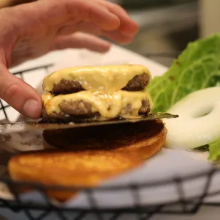 a hand grabbing a piece of cheeseburger
