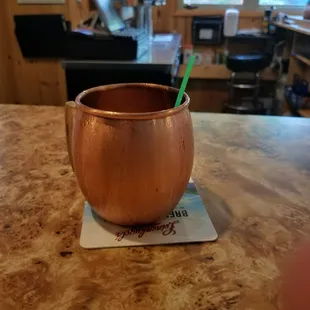 a copper mug with a green straw