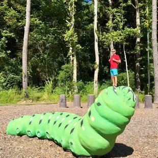 This playground is surrounded by big beautiful trees and an open field in the middle