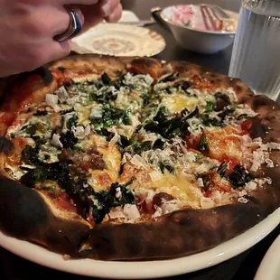 a person putting cheese on a pizza