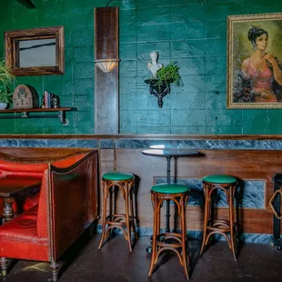 a green room with a red couch and two green stools