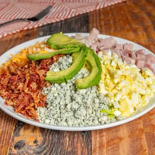 a plate of eggs, bacon, avocado, and blue cheese