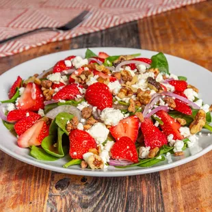 a plate of salad with strawberries and feta cheese