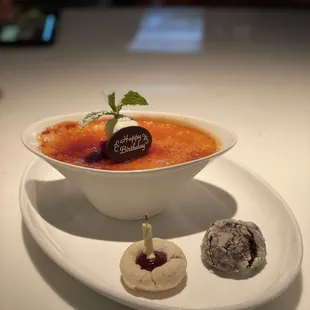 a bowl of creme with a small cookie on the side