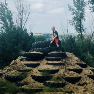 a boy sitting on a pile of tires