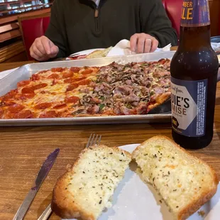 a man sitting at a table with a pizza and a beer
