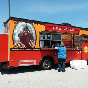a woman standing in front of a food truck