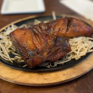 Grilled chicken leg on a sizzling plate