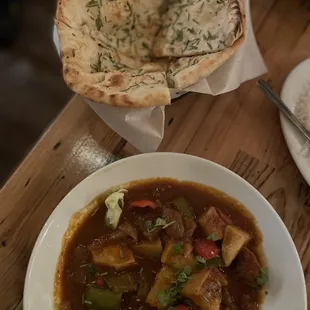 a bowl of stew with pita bread