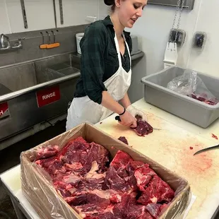 a woman in a kitchen preparing raw meat