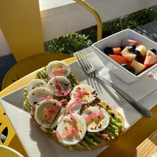 a bowl of fruit and a plate of eggs