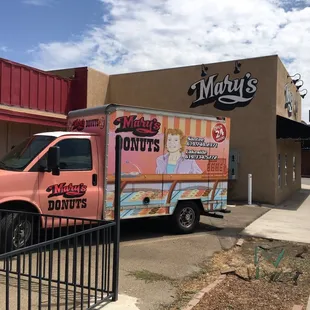 a pink truck parked in front of a donut shop