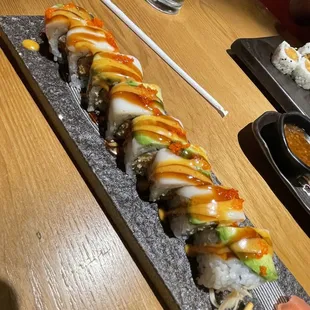 a sushi roll on a stone plate with chopsticks