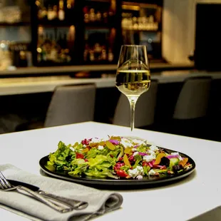 a plate of salad and a glass of wine
