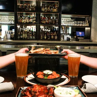two hands reaching for a plate of food