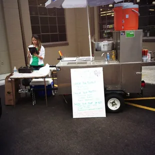 a woman standing in front of a food cart