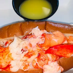 a lobster roll with a side of dipping sauce